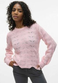 Helles rosa, gestricktes Sweatshirt mit Kabelmuster, mit gerippten Bündchen und Saum, kombiniert mit dunkelgrauen Hosen. Das Sweatshirt hat eine lockere Passform.