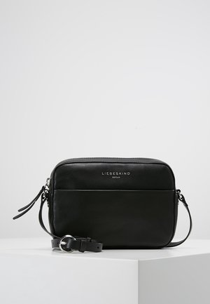 Sort rektangulær skuldertaske i læder med frontlomme, sølvspænde og "Liebeskind Berlin"-logo på en glat overflade.