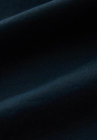 Donkerblauwe stof met een gladde textuur en fijne ribbels, met gelaagde plooien en subtiele variaties in licht.
