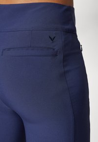 Navy leggings dengan tekstur halus, pinggang tinggi, dan saku belakang yang dilengkapi dengan jahitan ton-dan detail logo bordir.