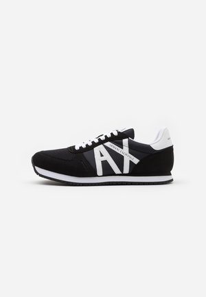 Czarne sportowe sneakersy z cholewką z siateczki i zamszu, z wyraźnym białym logo i sznurówkami oraz białą podeszwą środkową.
