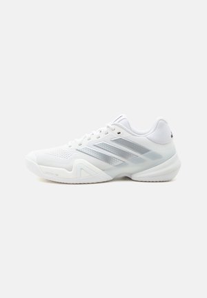 Weißer Sportschuh mit silbernen Streifen, Mesh-Struktur, dicker Sohle und Schnürdesign, dargestellt auf einfachem Hintergrund.