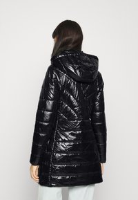 Czarna, błyszcząca kurtka puchowa z kapturem, z ukośnym wzorem pikowania, średniej długości i ściągnięta w talii dla dopasowanego kroju.