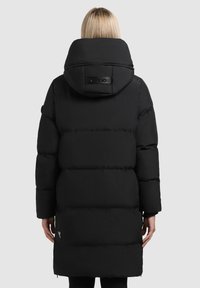 Giacca a vento nera con colletto alto, zip laterali e patch con logo sul retro. Presenta un motivo a rombi orizzontali e maniche lunghe.