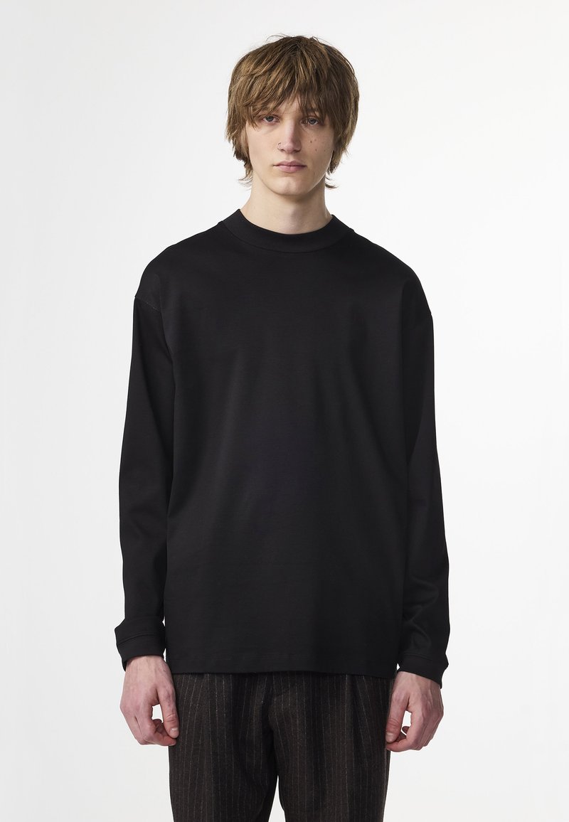 Black long-sleeve t-shirt made of cotton with a crew neck, featuring a relaxed fit and no visible patterns or accents.