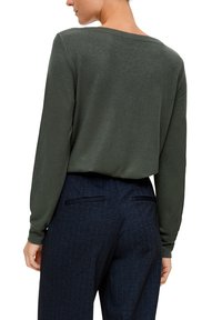 Haut à manches longues vert foncé avec un large décolleté, associé à un pantalon à rayures bleu marine. La texture douce et la coupe décontractée caractérisent l'ensemble.