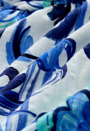 Close-up of textured fabric with a blue and white floral pattern in various shades and swirling designs.