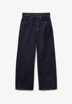 Donkerblauwe wijde denim broek met zakken aan de voorkant, knoopsluiting en zichtbare gele stiknaden op een witte achtergrond.