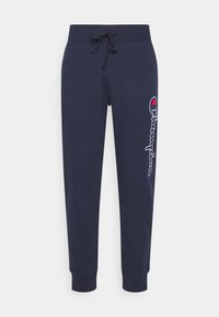 Tmavě modré teplákové kalhoty z měkké tkaniny, s elastickým pasem se stahovací šňůrkou a bílým vyšívaným logem podél levé nohy.