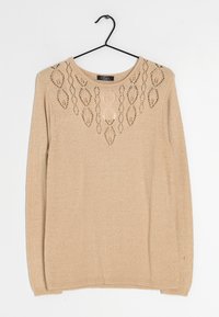 Maglione beige lavorato a maglia con scollo rotondo e un intricato motivo a traforo sulla parte superiore. Maniche lunghe e vestibilità comoda.