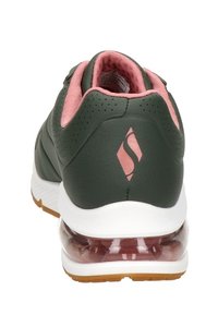 Gröna lädersneakers med rosa detaljer, perforerat mönster, vit sula och transparent hälkuddning. Logotyp på hälen.