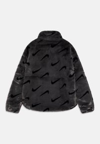 Černá fleece bunda Nike s vysokým límcem, měkkou texturou a opakujícím se vzorem loga, s dlouhými rukávy a uvolněným střihem.