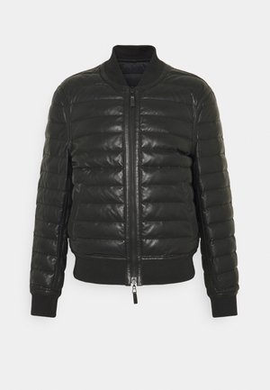 Chaqueta bomber acolchada negra con cierre zip, puños y cuello de canalé. Fabricada con un material brillante con textura acolchada horizontal.