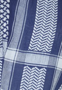 Modrá a bílá tkanina s alternujícími svislými pruhy, které obsahují rybí kost, kostkované vzory a geometrické vzory.