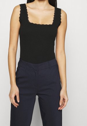 Czarne prążkowane body z kwadratowym dekoltem i koronkowym obszyciem. Połączone z granatowymi spodniami z wysokim stanem. Widok z przodu, modelka stoi, ręce wzdłuż ciała.