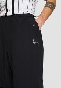 Svarta shorts i lätt material med resårmidja, sidofickdetaljer och vitt logomärke broderat på vänster framsida.