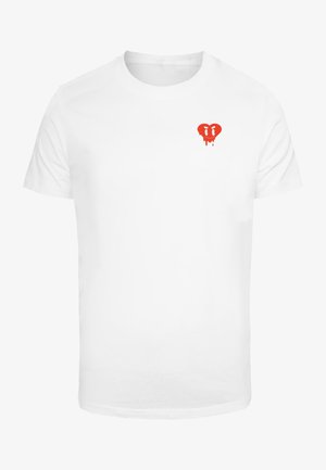 T-shirt bianca in cotone con una piccola grafica a forma di cuore rosso con dettagli gocciolanti nella zona del petto sinistro. Maniche corte e vestibilità standard.