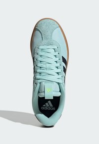 Jasnoniebieski but sportowy zamszowym czubkiem, czarnymi paskami i teksturowaną cholewką z tkaniny. Posiada gumową podeszwę i detale z logo.