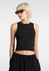 Black cropped tank top with embroidered "vans." logo, sleeveless design, and a fitted shape, paired with black, loose-fitting pants.