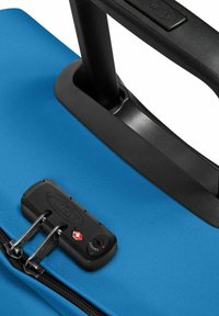 Valigia di tessuto blu con manico telescopico nero e lucchetto a combinazione. Presenta una zip robusta e una texture liscia.