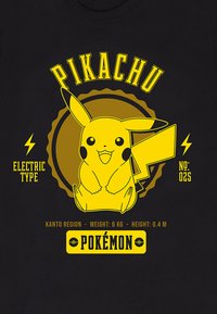 Černé tričko s grafikou žlutého Pikachu, obklopeného blesky, s textem popisujícím jeho elektrický typ a údaje z regionu Kanto.