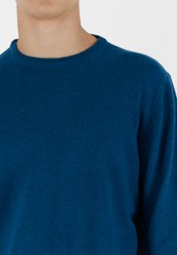 Niebieski sweter dziewiarski z okrągłym dekoltem, długimi rękawami i miękką fakturą, idealny do noszenia na co dzień. Brak widocznych wzorów lub logo.