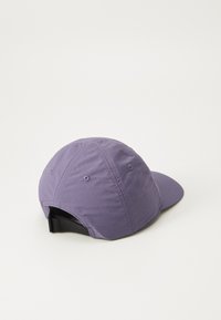Purple cap made of lightweight fabric, featuring a curved brim, fabric-covered button, and adjustable black strap at the back.