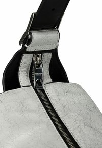 Borsa in pelle bianca testurizzata con zip argentata e dettagli neri. La tracolla è nera, con un dettaglio della fibbia metallica lucida.