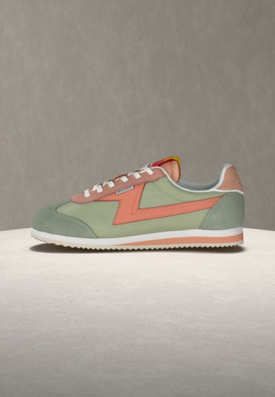 Green and pink low-top sneaker with white laces, zigzag design, white sole, and textured grip, placed on a neutral surface.