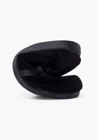 Scarpa nera senza lacci in morbido suede, con punta arrotondata e suola piatta. L'interno presenta una fodera testurizzata e un tassello per facilitare l'indosso.