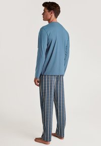 Lange mouwen, lichtblauw katoenen top gecombineerd met blauw-en-wit geruit pyjamabroek, met een relaxte pasvorm en zachte textuur.