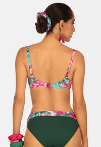 Zestaw bikini w kwiatowy wzór w odcieniach różu i zieleni, z tropikalnym motywem. Dół jest wykonany z zielonego materiału z pasem dopasowanym do góry.