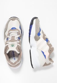 Adidas-sneakers med en blandning av beige och vit mesh, blå och grå accenter, vadderad krage och gummisula med ett texturerat mönster.