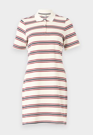 Rochia polo are o bază crem cu dungi orizontale în roșu, bleu marin și alb. Dispune de guler, mâneci scurte și o formă ajustată.