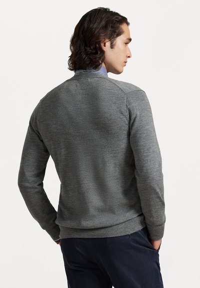 Grå stickad tröja med rund hals och ribbade muddar och nederkant. Mjuk textur och klassisk design. Bärs över en skjorta med krage.