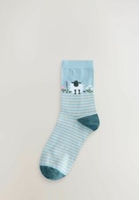 Chaussette rayée bleu clair avec un motif de mouton blanc aux détails noirs et des accents floraux verts au niveau du bord et des orteils.