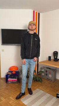 Μαύρο φούτερ με φερμουάρ και μπροστινές τσέπες, ανοιχτό μπλε τζιν και σκούρα καφέ παπούτσια. Απλός σχεδιασμός με εκτυπωμένο λογότυπο στο φούτερ.