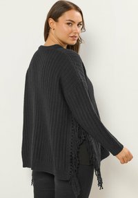 Czarny sweter z prążkowanego dzianiny z długimi rękawami, bocznymi frędzlami i luźnym krojem. Teksturowana tkanina, otwarty fason po bokach oraz okrągły dekolt.