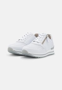 Vita sneakers med ovandel i slätt läder, mesh-detaljer, justerbar snörning, sidodragkedja och en lätt grå gummisula.