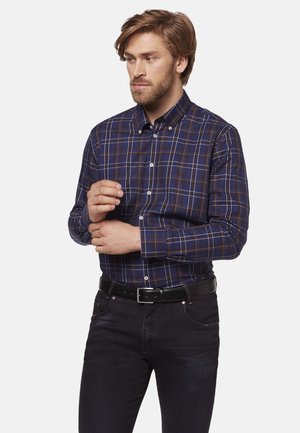 Navy checkered button-up shirt with orange and white lines, long sleeves, and a classic collar, paired with dark jeans and a black belt.