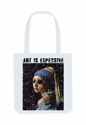 Donna con orecchino di perla che indossa occhiali da sole e un foulard firmato, con la scritta "L'ARTE È COSTOSA" sopra su una borsa a spalla bianca.