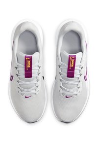 Baskets de sport grises avec des accents violets, en tissu en maille, avec des semelles blanches et un logo Nike noir. Elles possèdent une languette texturée avec un branding violet.
