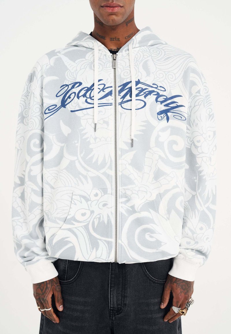 Felpa con cappuccio e zip di colore grigio chiaro con un sottile motivo bianco e testo blu. Presenta lacci e polsini a coste.