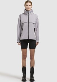 Light gray waterproof jacket with high collar, front zip, and side pockets. Paired with black shorts and ankle-height black boots.