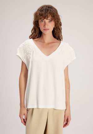 Witte korte mouwen top met een V-hals en textuur bloemen accenten op de schouders. Zachte stof met een relaxte pasvorm.