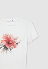 T-shirt bianca con una grande stampa colorata di un fiore di ibisco in tonalità di rosa e rosso, con foglie verdi e un classico colletto a girocollo.