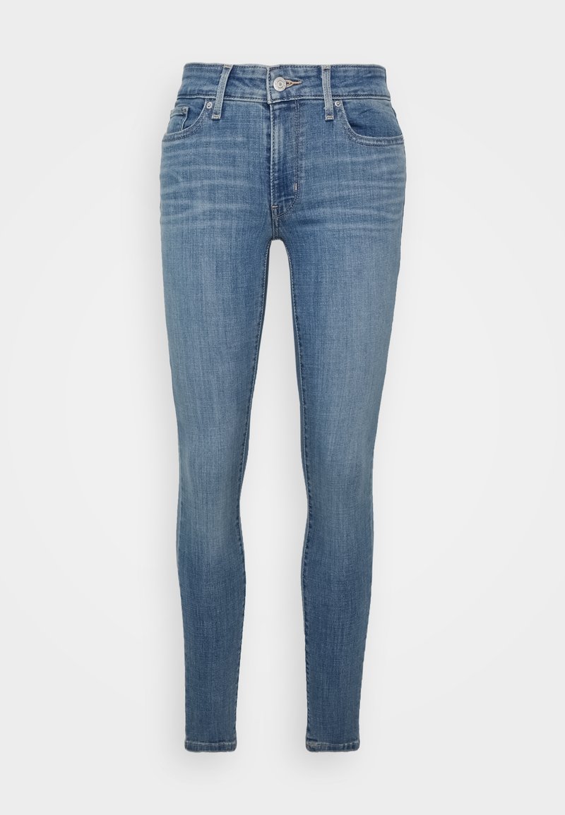 Jean skinny bleu clair avec poches avant, passants pour ceinture et fermeture par bouton, présenté sur un fond blanc uni.