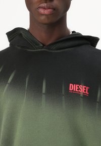 Φούτερ με κουκούλα σε μαύρο και πράσινο gradient, με κόκκινο λογότυπο "DIESEL" στο στήθος και αντιθετικά ραψίματα στην κουκούλα.