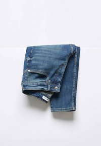 Folded blue denim jeans with visible front pocket, button, and belt loops on a white surface.