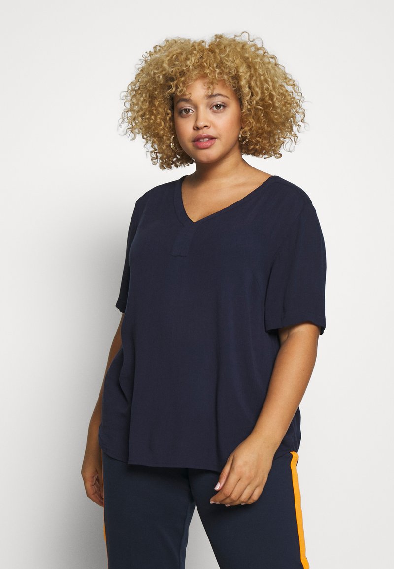 Navy blue V-paitsi t-paita lyhyillä hihoilla, valmistettu pehmeästä kankaasta; siinä on rento istuvuus ja lievästi tiputettu olkapäädesign.